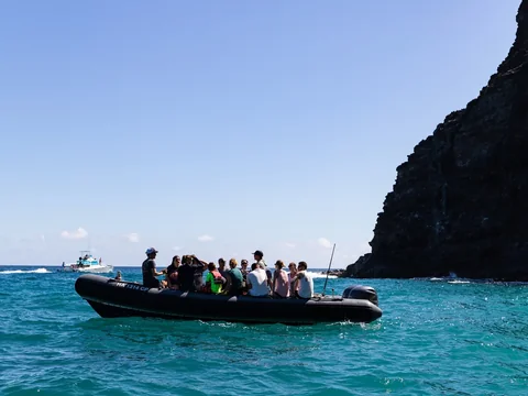 A boat below the green sea cliffs of the Nā Pali Coast