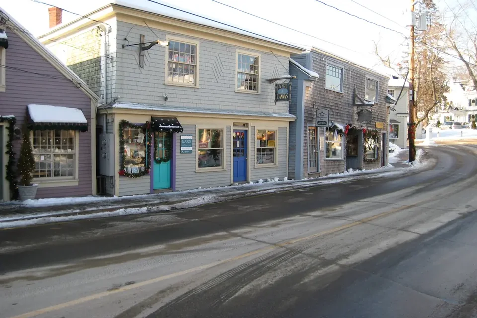 Ocean Avenue in Kennebunkport in winter, with snowbanks along the road and shops on both sides