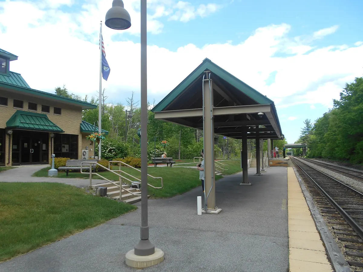 The Downeaster platform at Wells station in Maine, with a canopy shelter and lamps beside the track