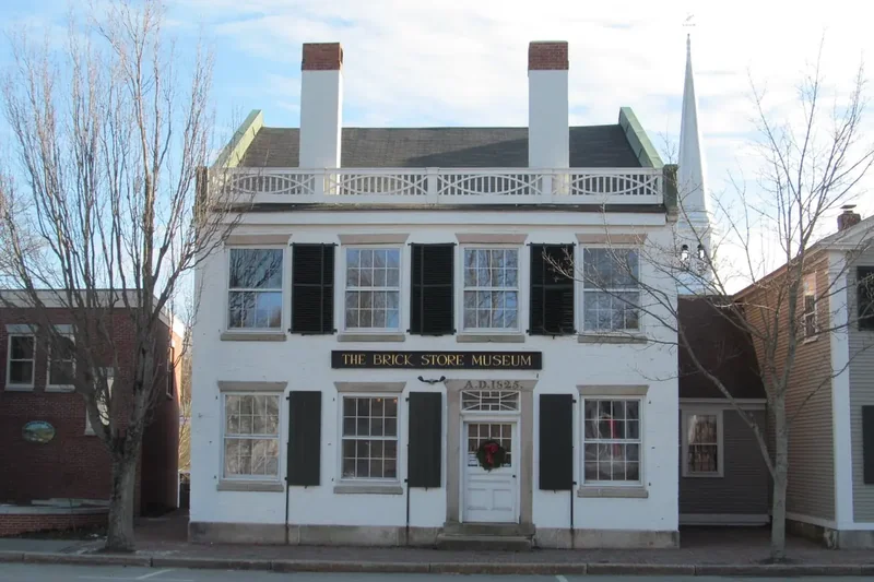 The white facade of the Brick Store Museum building on Main Street in Kennebunk, under bare trees