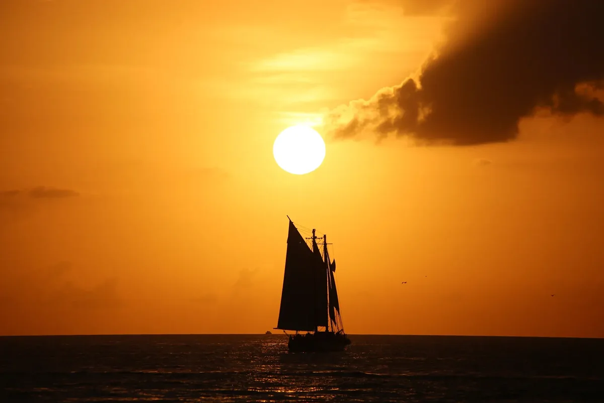 The sun setting over the water off Mallory Square in Key West, with a schooner in silhouette