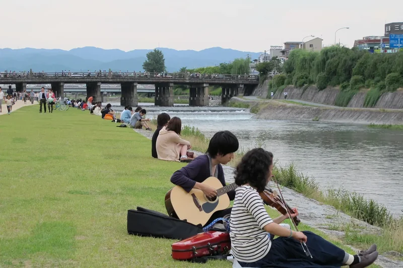 Couples sitting along the bank of the Kamo River in Kyoto