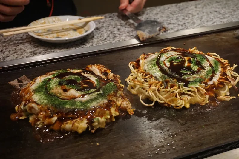 Okonomiyaki cooking on a teppan griddle in Osaka