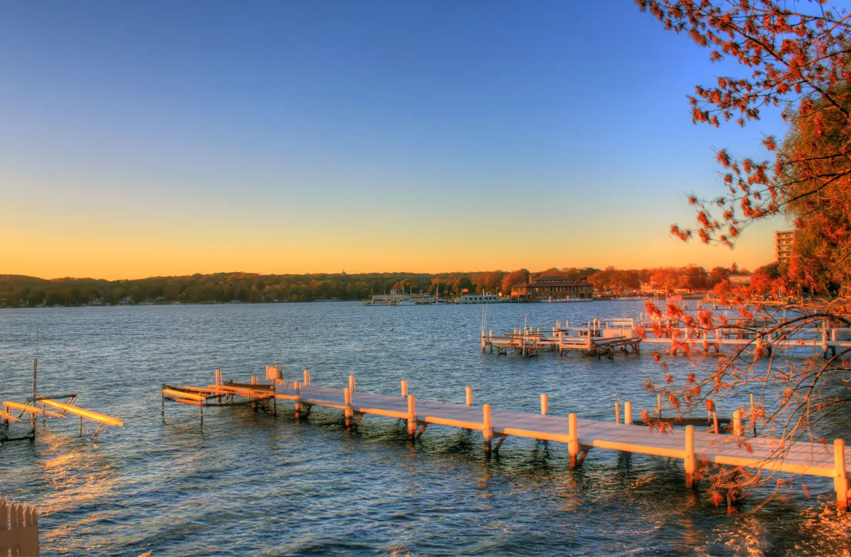 Boat docks on Geneva Lake at dusk, with a calm lake and a colorful sky