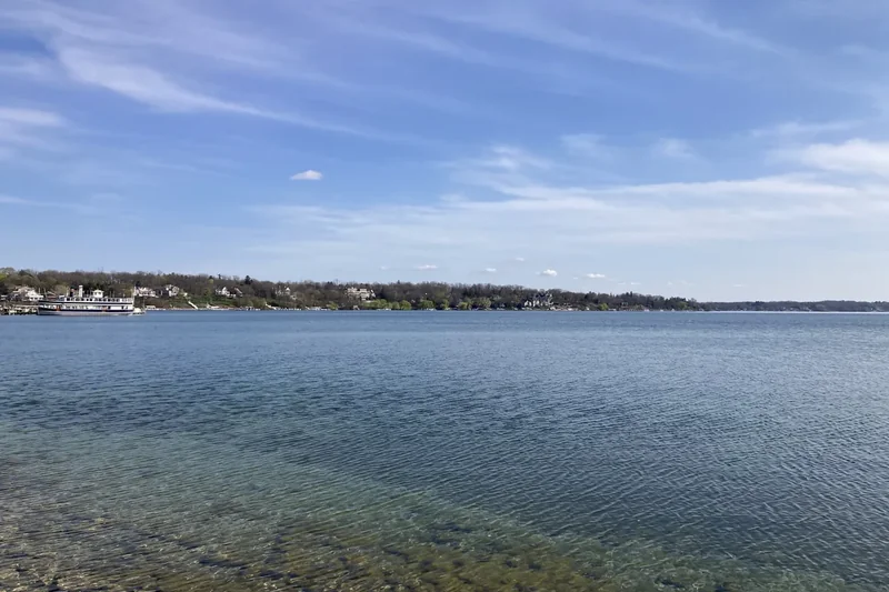 Geneva Lake, clear blue water with a wooded shoreline under a wide sky