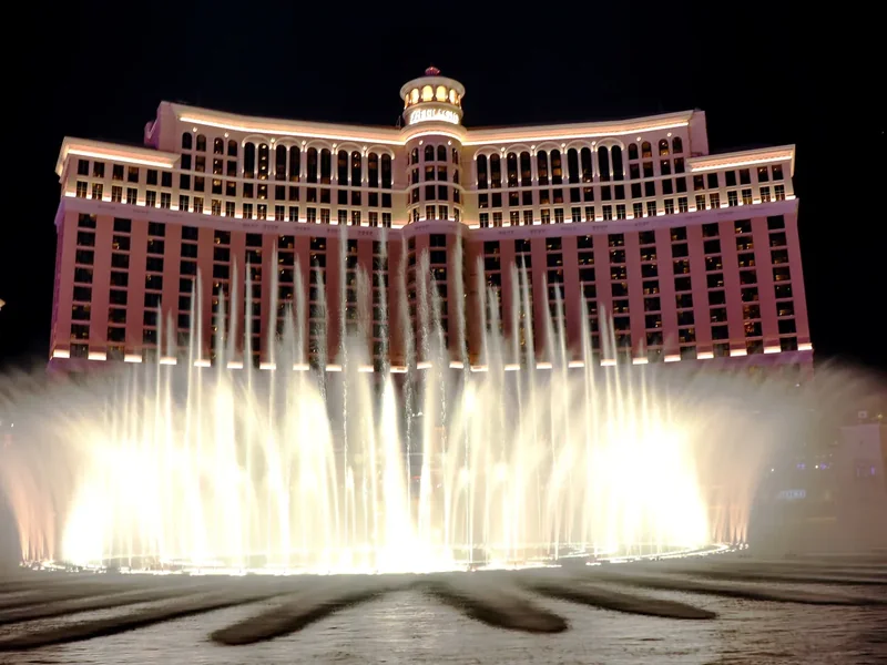 The Fountains of Bellagio shooting white jets of water in front of the lit hotel at night