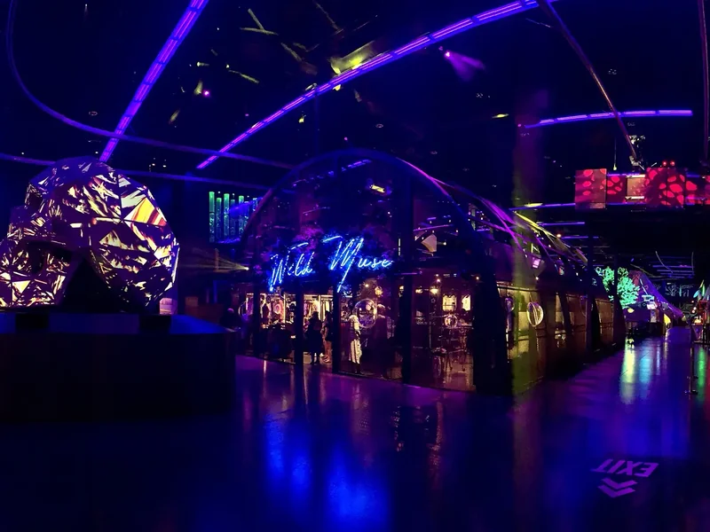 A dark indoor hall at AREA15 lit in purple and blue with a large glowing sculpture