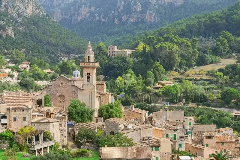 The stone village of Valldemossa with its church bell tower beneath the Tramuntana peaks