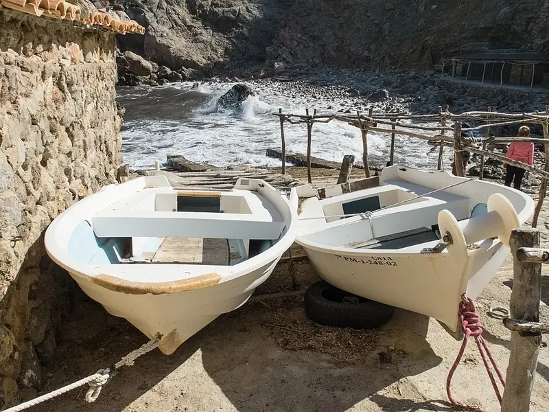 Boats anchored in the cove at Cala Deià beneath the cliffs