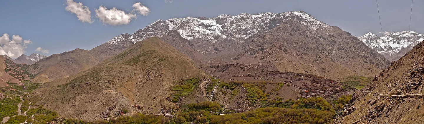 The High Atlas above Imlil, snow on the Toubkal massif over terraced walnut groves and red-earth villages.