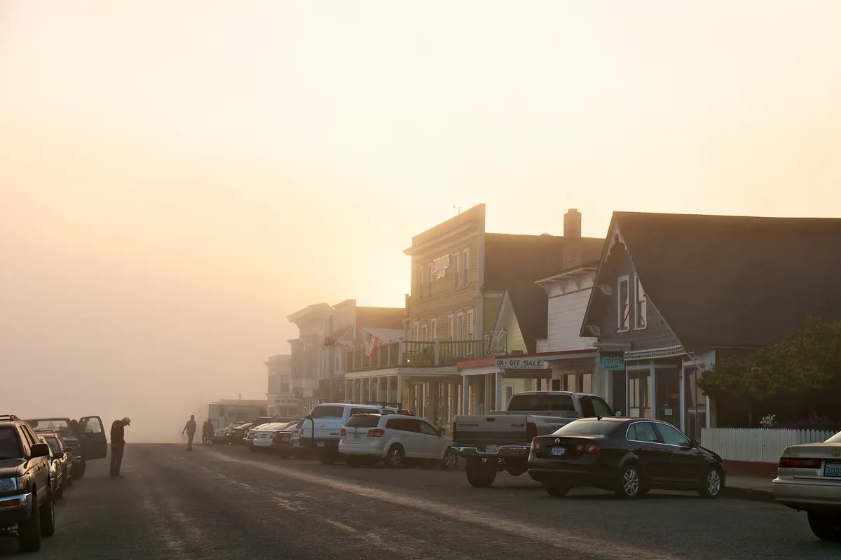 Fog over Main Street in Mendocino with the sun trying to break through above old wooden buildings