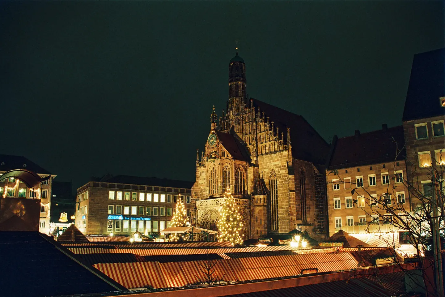 Photo: Nuremberg’s Hauptmarkt after dark, lit Christkindlesmarkt stall roofs below the Frauenkirche.