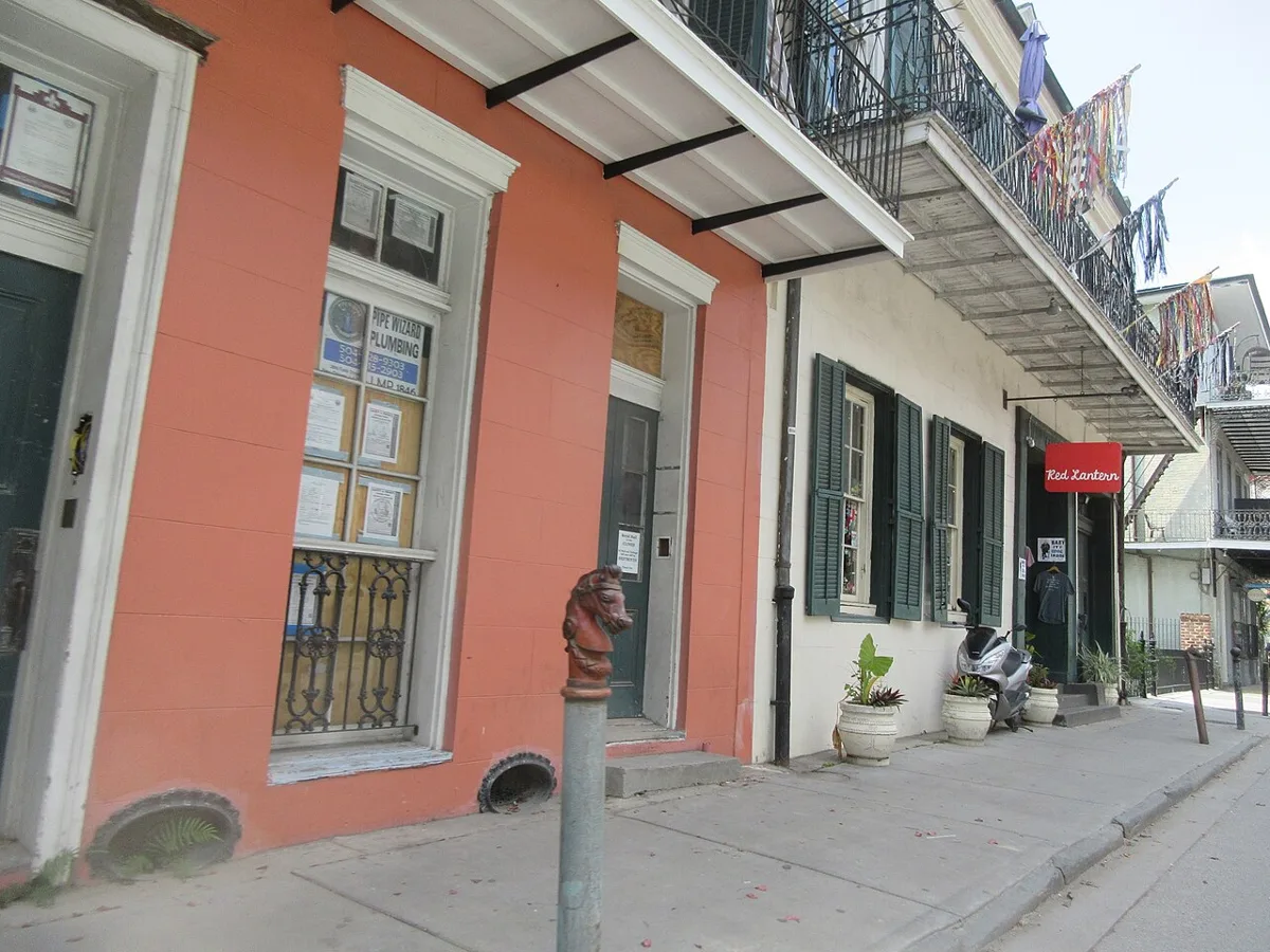 A coral-and-cream Creole townhouse with green shutters and an iron balcony on Royal Street in the French Quarter