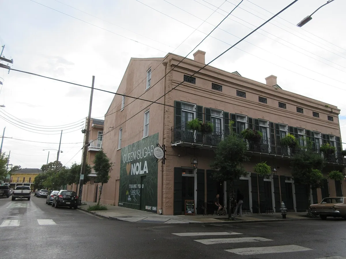 A two-storey brick building with green shutters and plant-hung iron balconies at Frenchmen and Royal Streets in the Marigny
