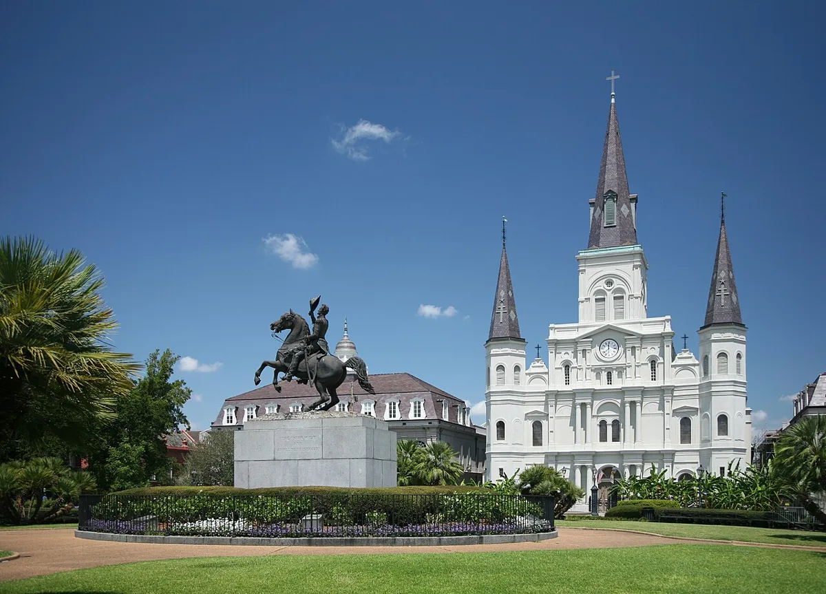 Jackson Square in New Orleans, the Andrew Jackson statue in front of the white triple-spired St. Louis Cathedral under a blue sky