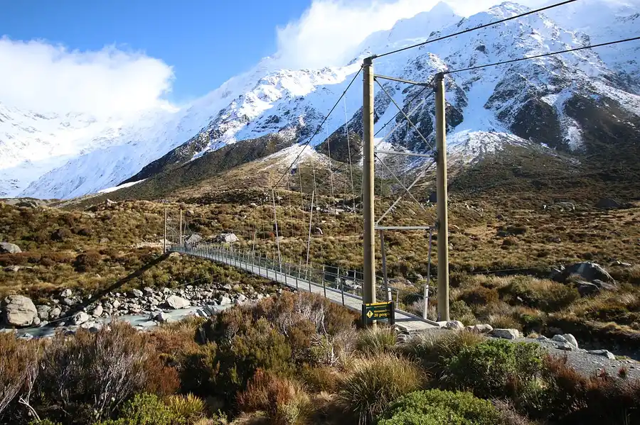 A swing bridge on the Hooker Valley walk beneath snowy peaks