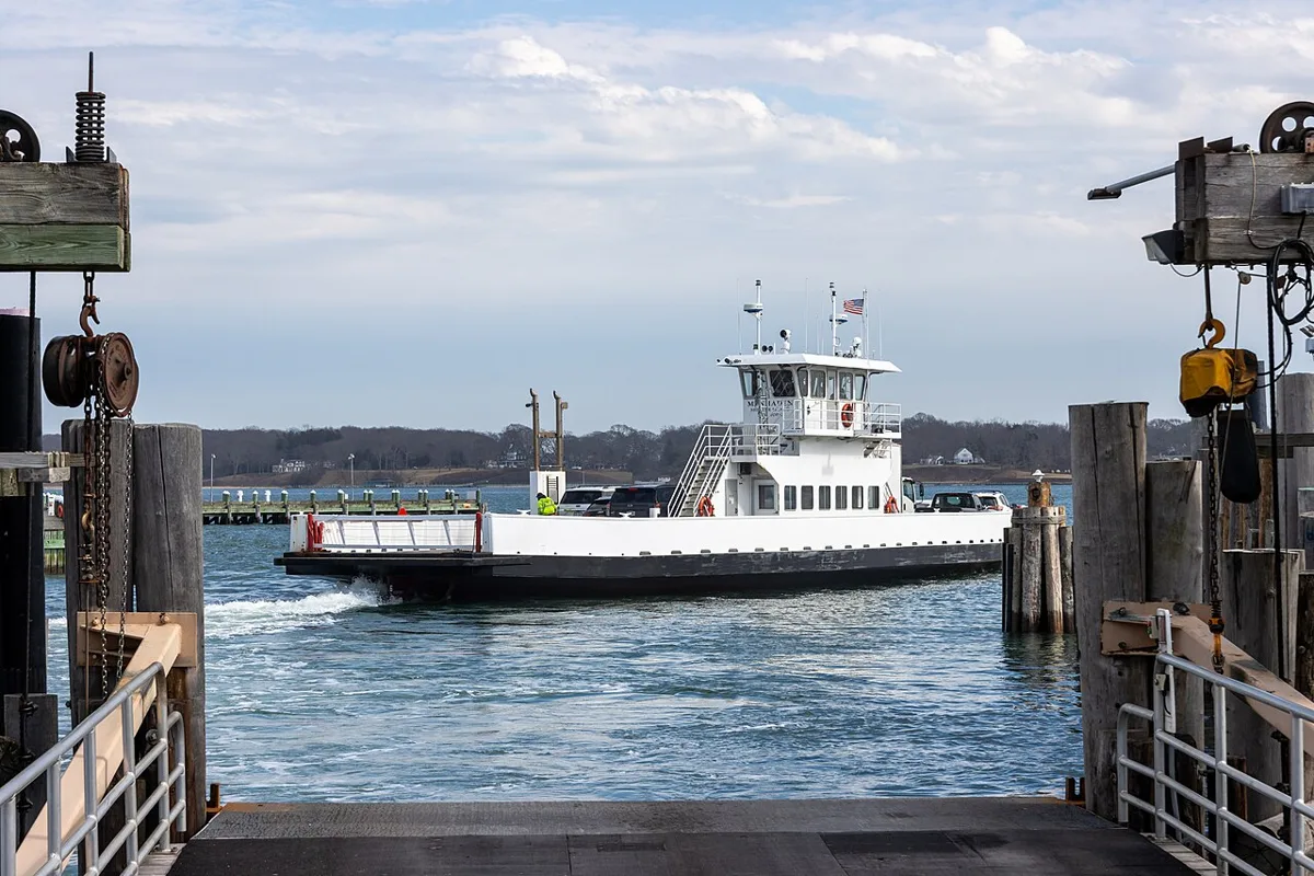 A white North Ferry boat crossing the harbor toward the Greenport slip, seen from the ferry dock