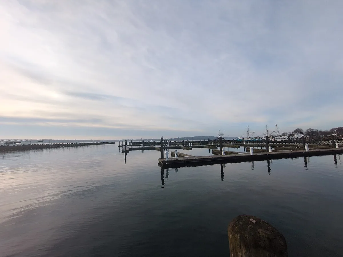 Greenport Harbor on a calm spring morning, with docks, moored boats and the water reaching across to Shelter Island