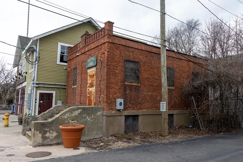 An old red-brick building beside a green clapboard house on a Greenport side street
