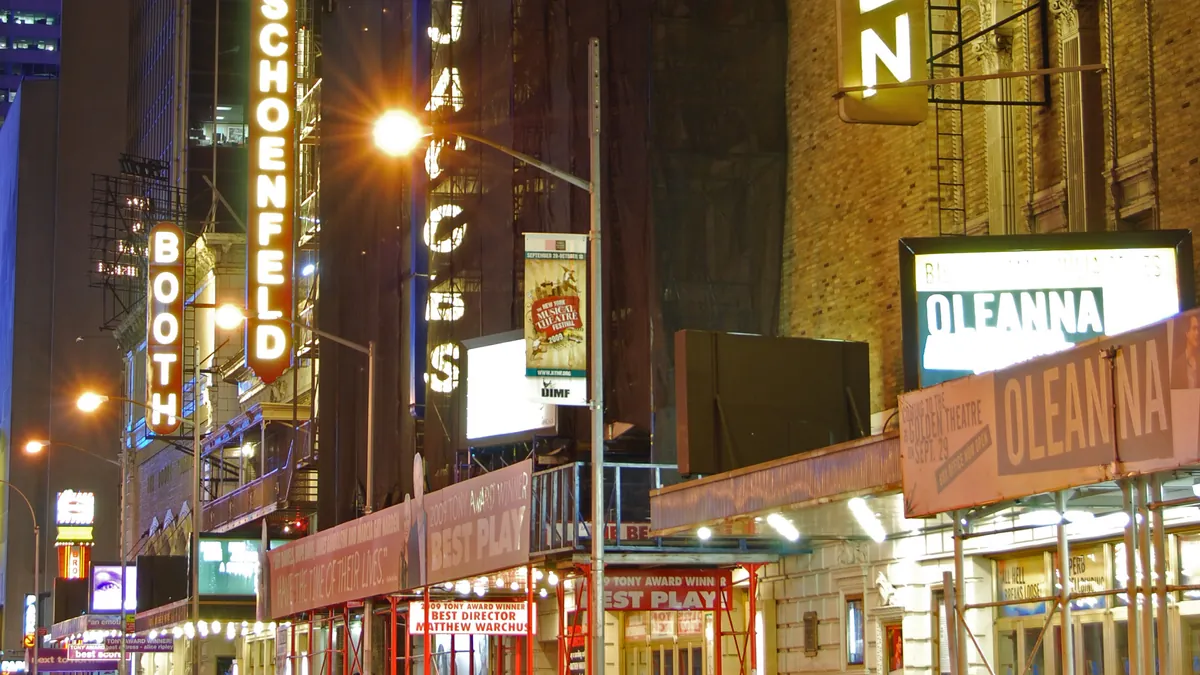 The lit marquees of Broadway theaters along West 45th Street at night in the Theater District