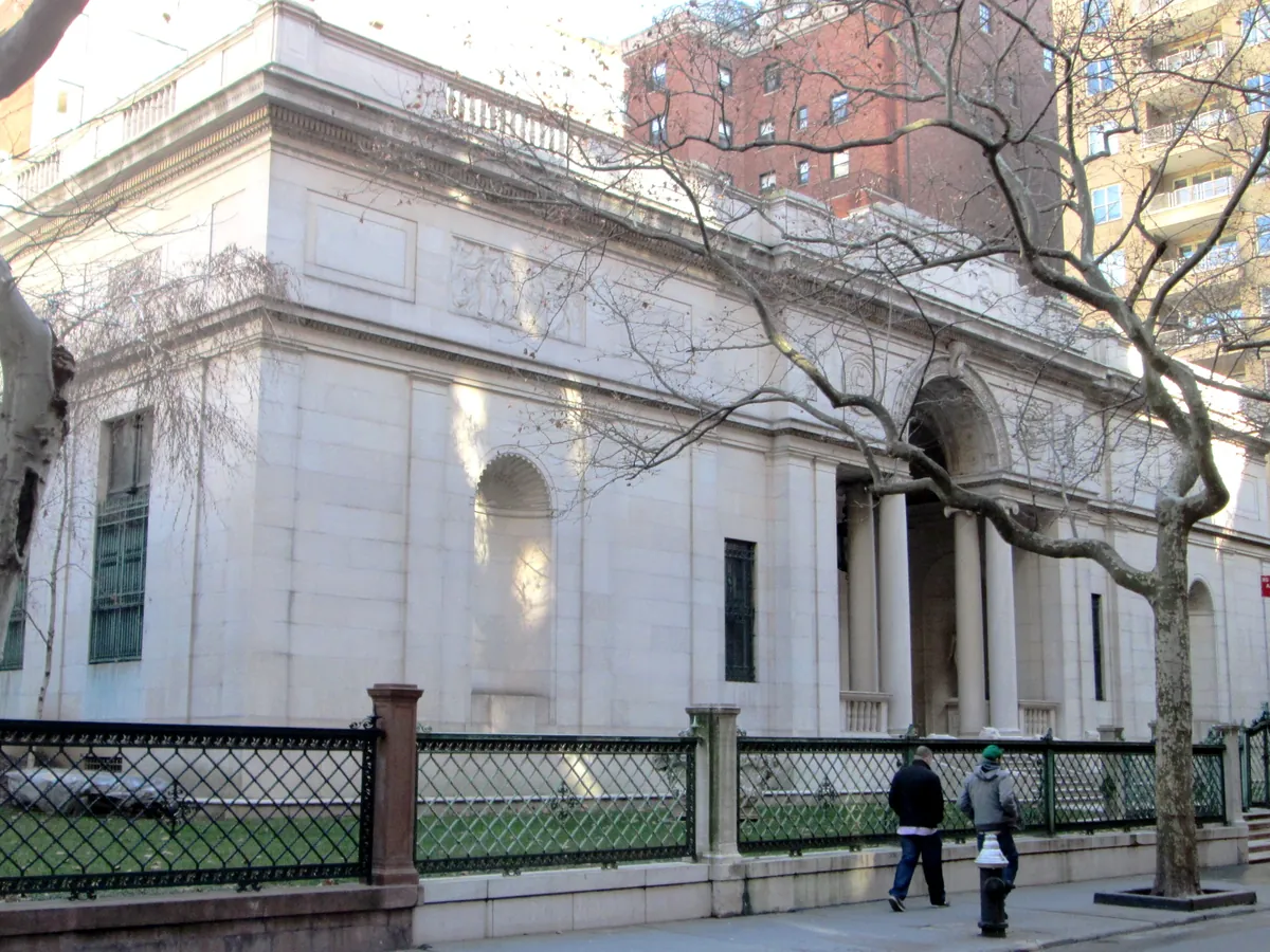The pale stone McKim building of the Morgan Library on a Murray Hill street, with its columned entrance between two lions