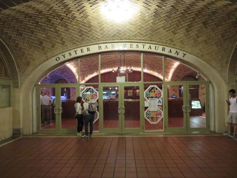 The dining room of the Grand Central Oyster Bar under low vaulted tile ceilings, with tables and the long counter