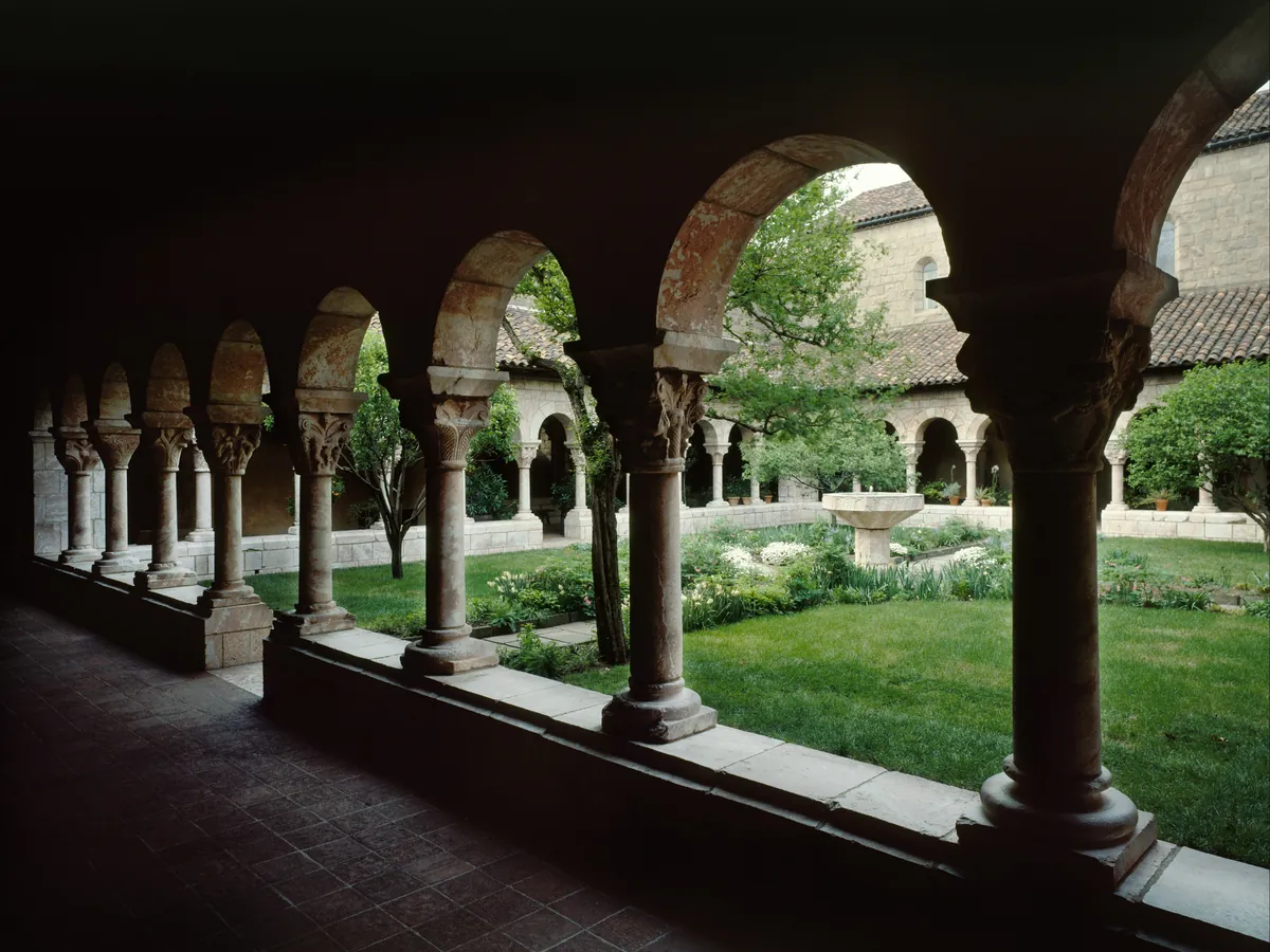 The arcades of the Cuxa Cloister at the Met Cloisters, with pink marble columns around a garden