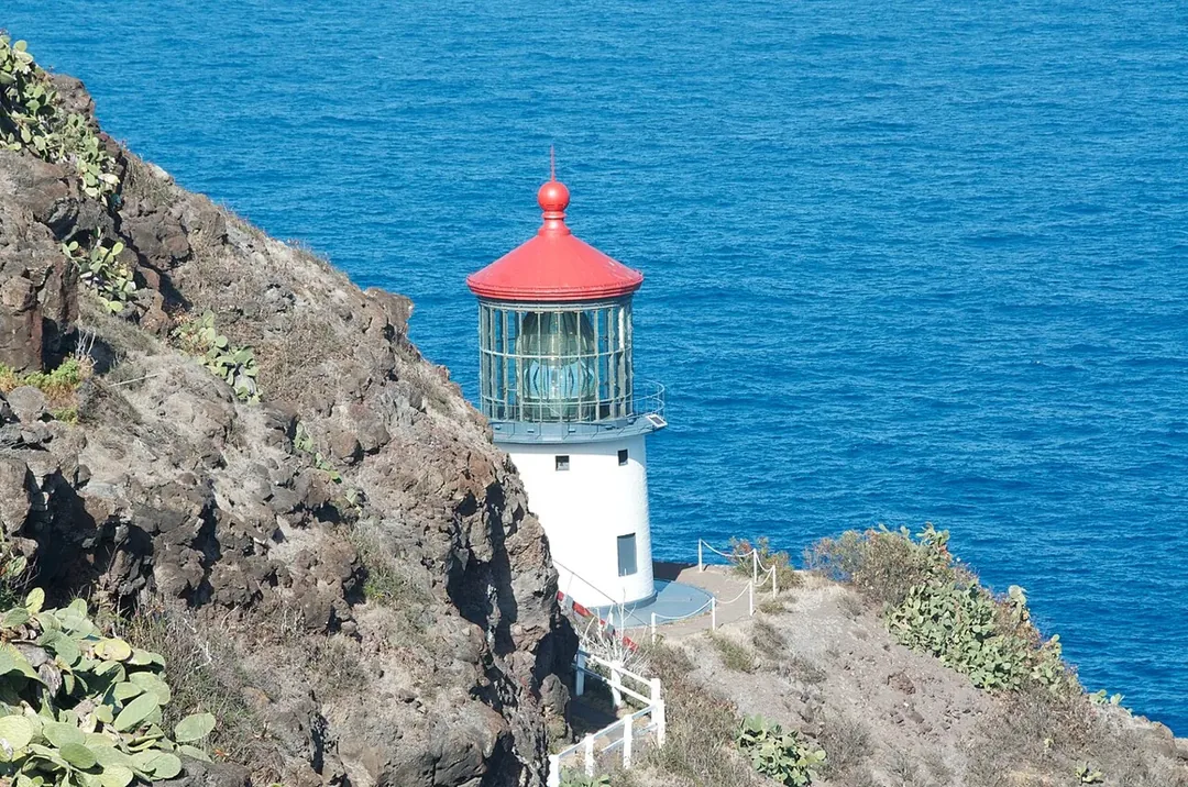 The red-roofed Makapuʻu Point Lighthouse on rocky cliffs above the blue ocean