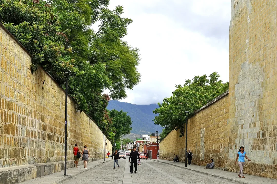 A street in the Centro of Oaxaca de Juárez beside a long wall of green cantera stone