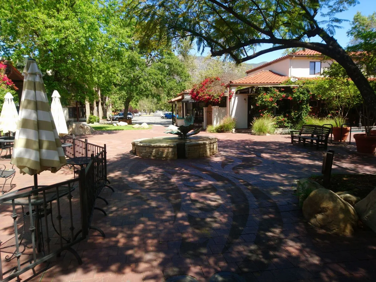 A fountain in the shaded courtyard of the Ojai arcade, with trees, benches and tiled paving