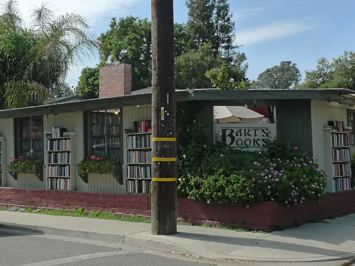 The open-air shelves of Bart’s Books along a sidewalk in Ojai, under trees