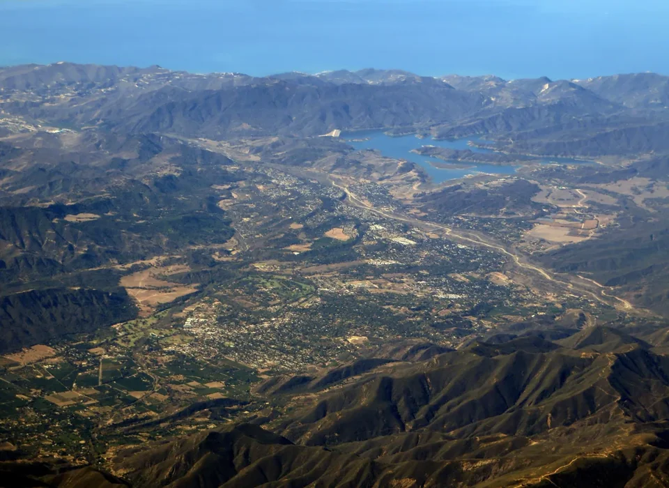 A view across the green Ojai Valley with orchards, houses and mountains