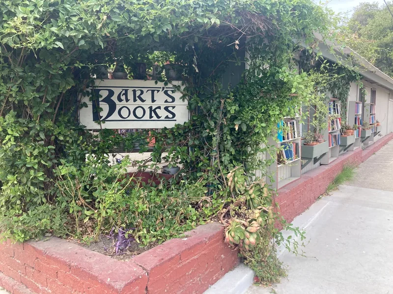 The entrance of Bart’s Books with its sign, climbing plants and bookshelves along the wall