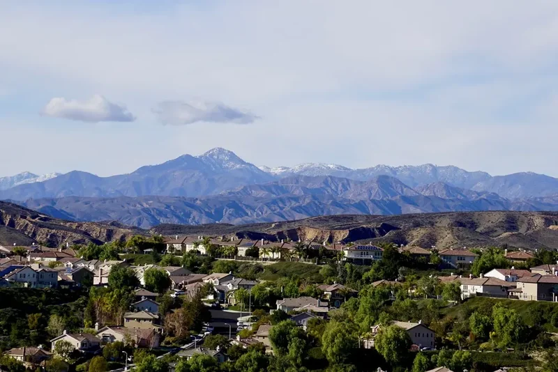 Snow-dusted Topatopa Mountains above houses and trees in the Ojai Valley