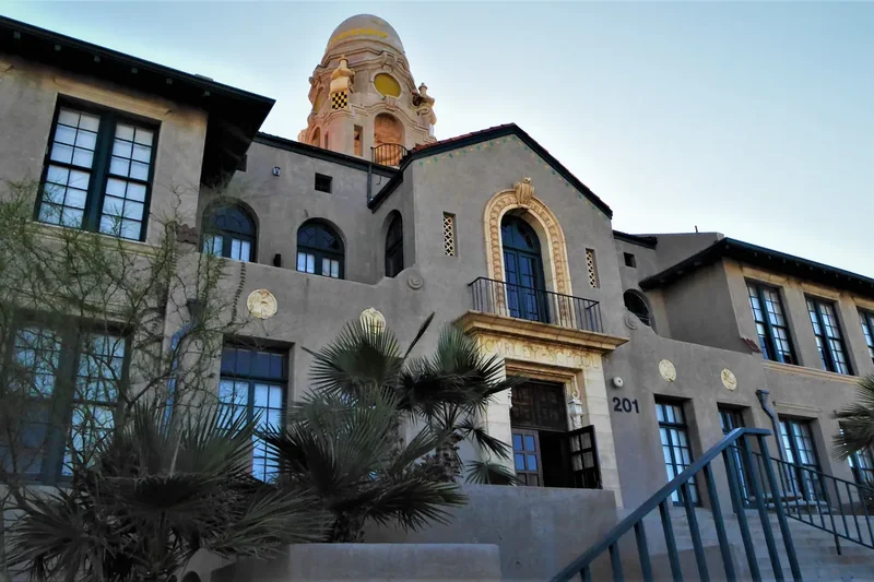 A cream-colored Spanish Colonial Revival building with arched windows and a tiled roof in Ajo