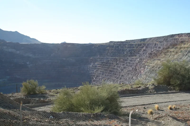 The terraced walls of the old open-pit copper mine at Ajo, with tailings and desert hills beyond