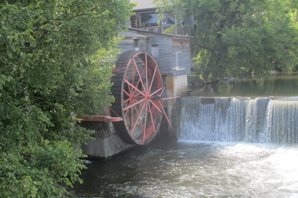 The red waterwheel of the Old Mill beside a waterfall on the Little Pigeon River