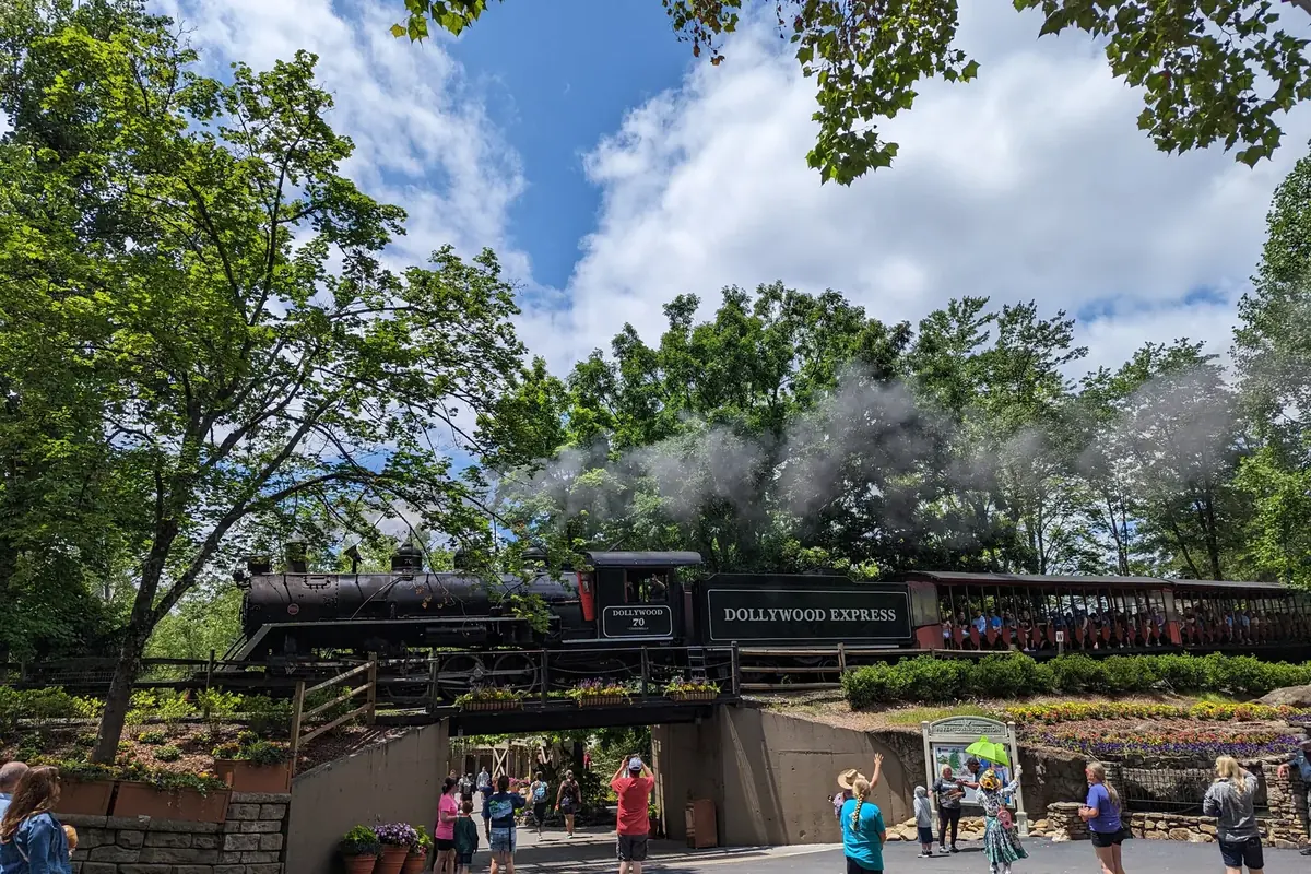 The Dollywood Express steam train with its cars in the park, trees and smoke around it