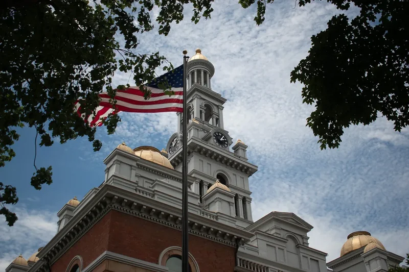The Sevier County Courthouse clock tower with a US flag in front