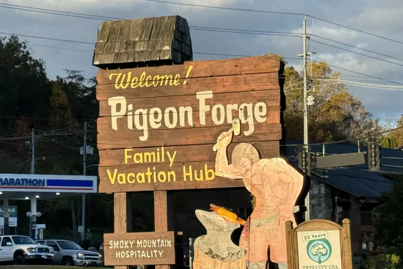 The wooden Welcome to Pigeon Forge sign with a carved figure beside it