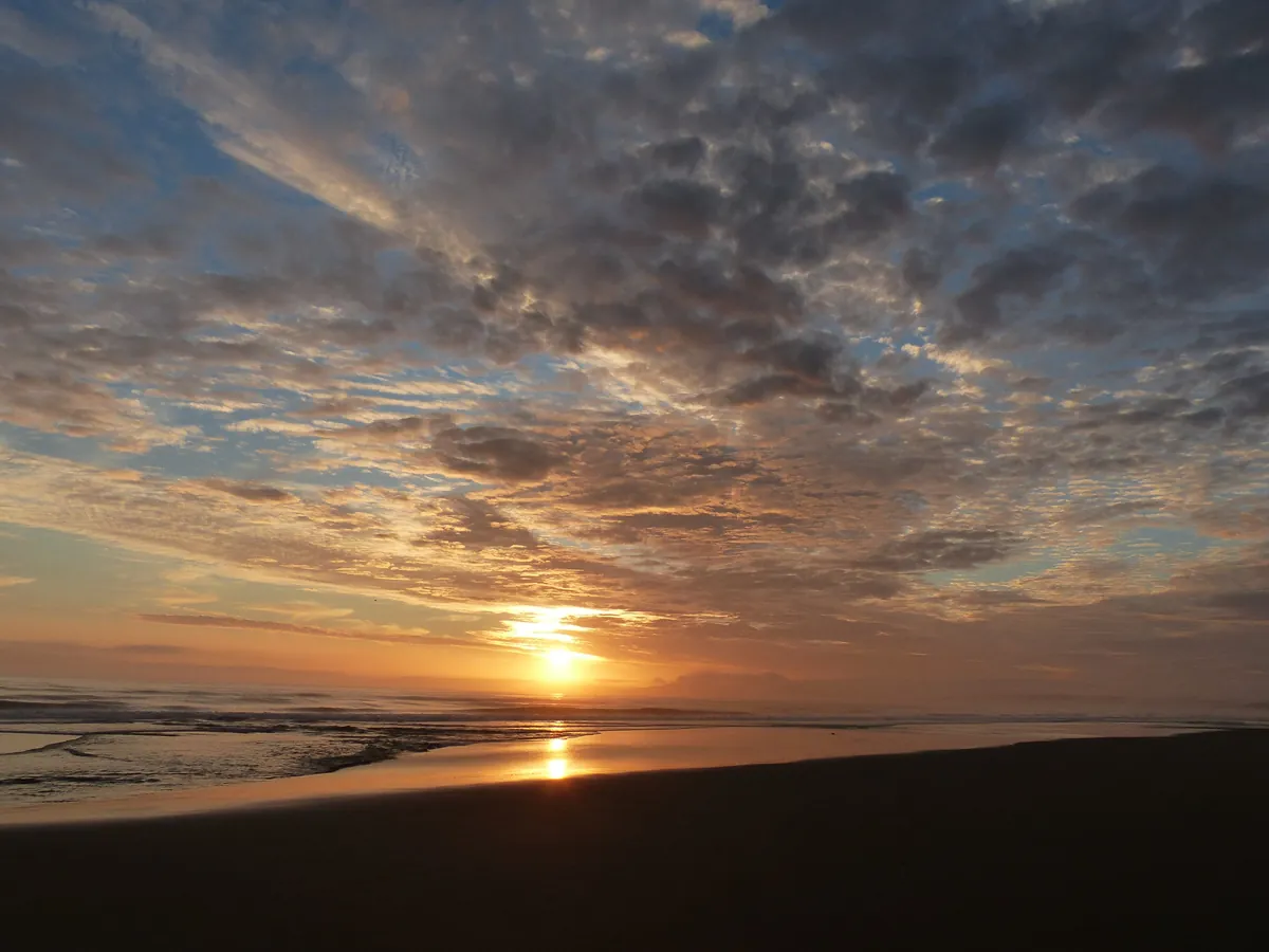 The sun setting over the sea at Limantour Beach under dramatic clouds