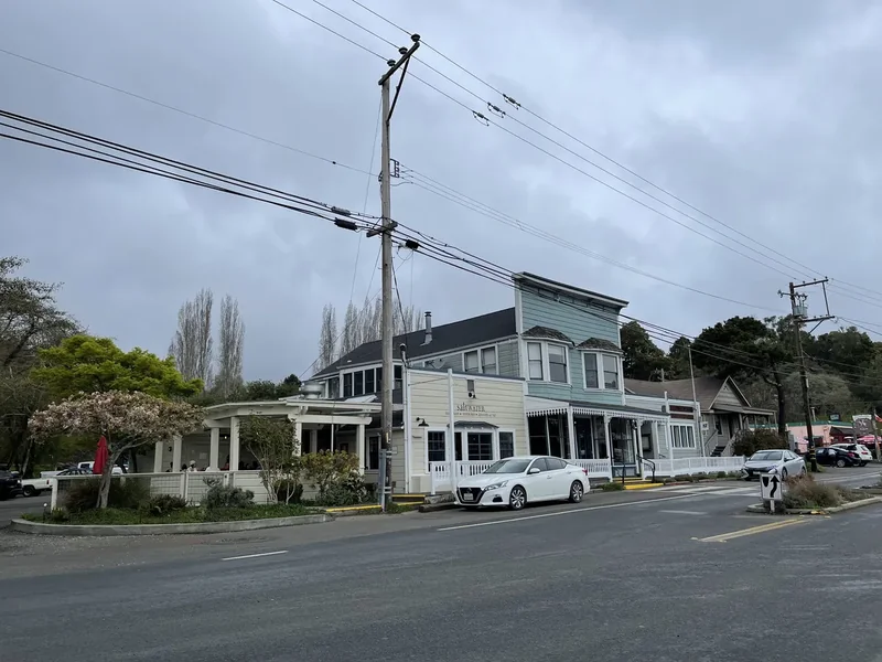 A white wooden building and trees along the road through Inverness