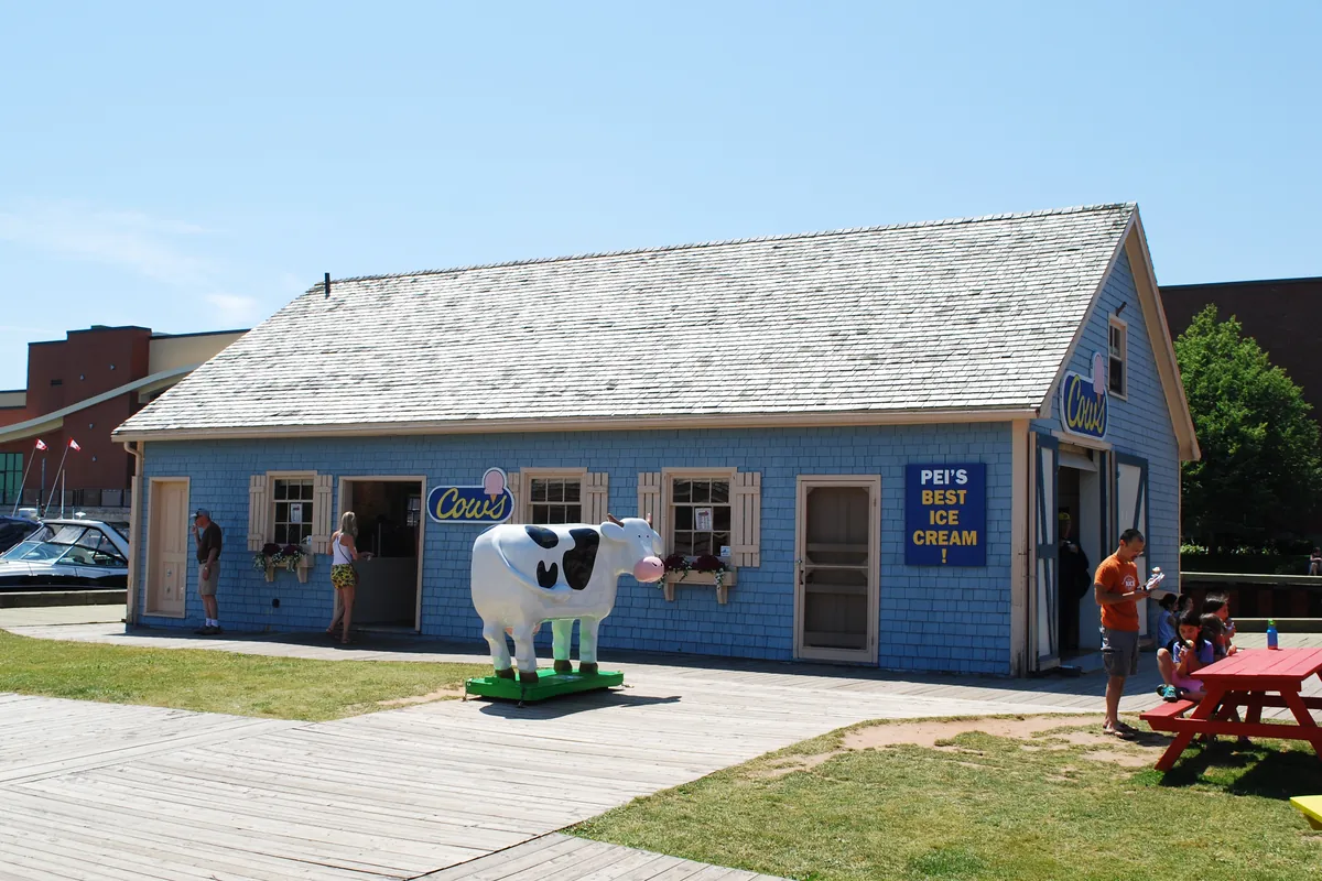 The blue clapboard COWS ice cream shop on Peake’s Quay in Charlottetown, with a cow statue and a picnic table