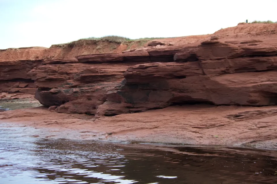 Low red sandstone ledges and rocks along the shore in Prince Edward Island National Park