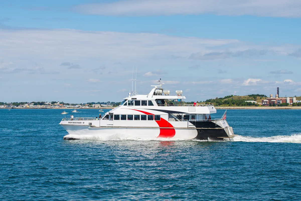 A white passenger ferry crossing the water away from Provincetown toward Boston
