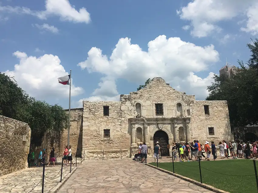 The Alamo mission facade with the Texas flag in red rock formations