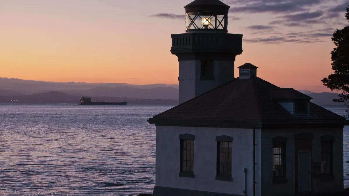 The small white Lime Kiln lighthouse on dark rocks above Haro Strait on San Juan Island