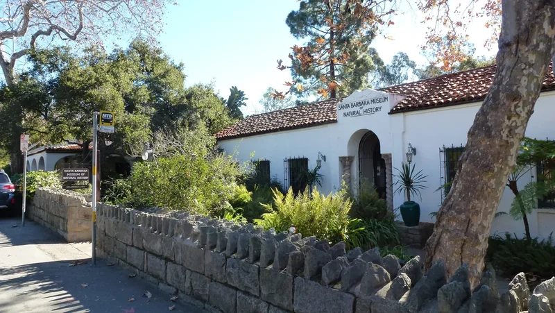 The stone and tile exterior of the Santa Barbara Museum of Natural History among oaks