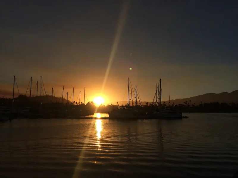 Sunset over Santa Barbara Harbor with masts against the sky
