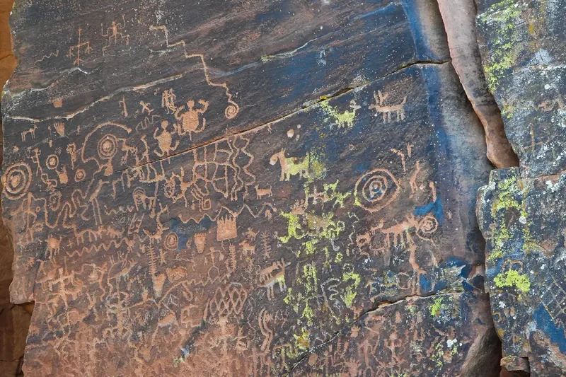 Petroglyphs of animals, spirals and figures carved on a dark sandstone panel at the V Bar V site